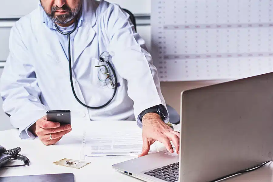 A doctor referencing his mobile phone for a one-time password, an example of a "what you have" factor.