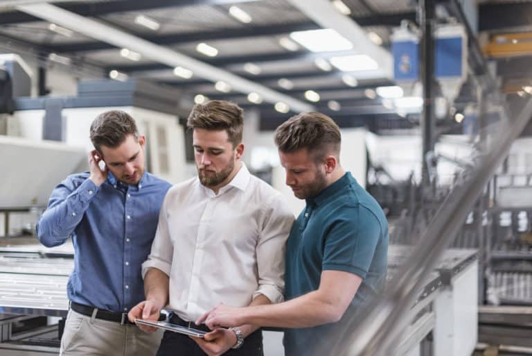 Three employees utilizing enterprise Wi-Fi on a factory floor, which would be difficult without a server running on-premises Active Directory.